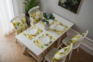 Detail of yellow lemon print placemats and pillow covers on a white dining table set