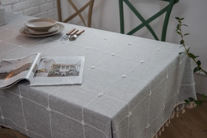 Detail of grey checkered tablecloth with white tufts and decorative tassel fringe edges