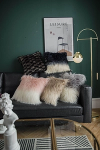 Detail of plush faux fur cushion covers in various gradient colors on a modern sofa