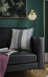 Detail of gray striped decorative pillow on black leather sofa with high-end indoor lighting