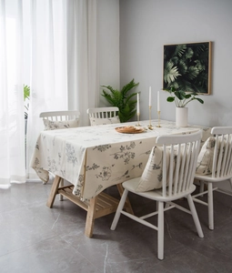 Detail of linen tablecloth with grey floral prints and matching cushions in dining room