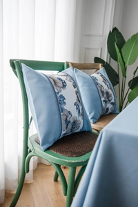 Close-up of light blue decorative pillow with vintage floral embroidery on a rustic chair