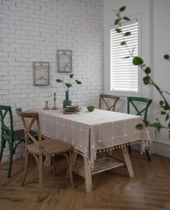 Close-up of checkered embroidery on beige cotton linen tablecloth with fringe edges