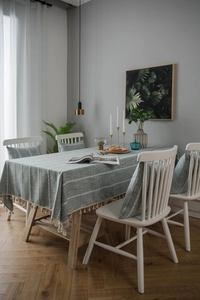 Detailed close-up of textured cotton linen tablecloth with elegant beige tassel fringe