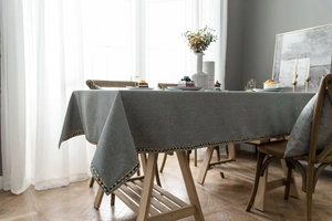 Detailed view of grey linen tablecloth featuring colorful geometric embroidery on the edge