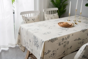 Detailed close-up of beige cotton linen tablecloth with dark gray floral sketch pattern