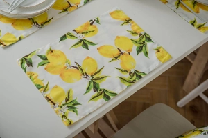 Detail of linen placemat featuring realistic lemon fruit prints and green foliage patterns