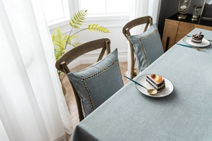 Detail of light blue linen tablecloth and matching cushions with geometric weave patterns