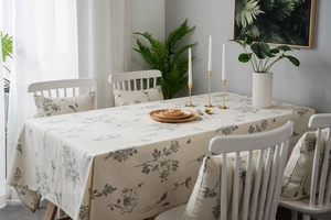 Detailed close-up of linen tablecloth featuring black floral botanical prints and matching cushions