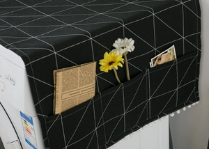 Detail of black geometric fridge dust cover with side storage pockets and white pompom trim
