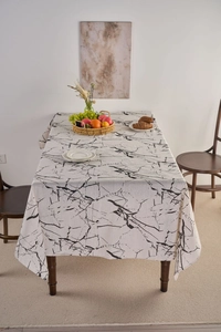 Detailed view of white marble print tablecloth on a dining table in a cozy home setting