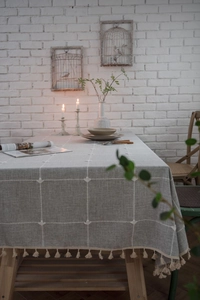 Detailed view of gray checkered tablecloth featuring white heart embroidery and beige tassels