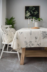 Detail of grey bee and floral print on beige linen tablecloth in a cozy dining setting