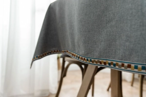 Detail of grey tablecloth showing textured fabric with colorful geometric embroidery borders