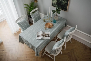 Close-up of gray-green cotton linen tablecloth with white embroidery and tassels