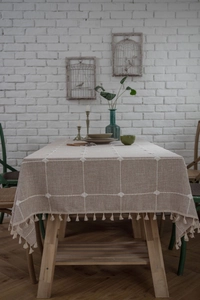 Close-up of embroidered grid pattern and tassels on khaki cotton linen tablecloth