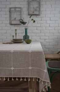 Detail of light coffee cotton linen tablecloth with white grid lines and fringe tassels