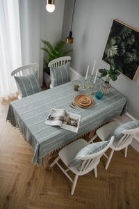 Detail of grey-blue cotton linen tablecloth with white embroidery stripes and tassels