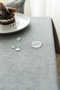 Detailed view of waterproof grey-blue linen texture tablecloth with water droplets