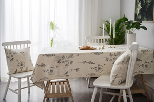 Close-up of linen tablecloth and matching pillows with black floral sketches