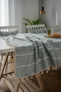 Detailed view of sage green cotton linen tablecloth with white tassels and embroidery