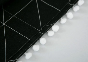 Detail of geometric pattern fridge cover with decorative white pom-pom fringe edges