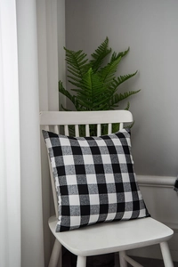 Close-up of a classic black and white buffalo check pillow cover on a white wooden chair