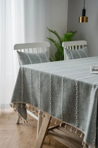 Close-up of linen table cloth with white wave stripes and beige tassel fringe detailing
