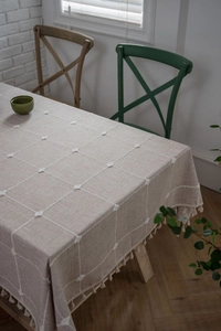 Detailed view of checkered cotton linen tablecloth with elegant tassels and woven texture
