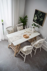 Detail of floral table runner and matching cushion covers on a modern wooden dining table