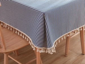 Detail of blue and white striped rectangular tablecloth with beige tassel fringe edge