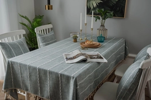 Close-up of striped embroidered linen tablecloth with fringe edges and matching cushions