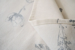 Macro shot of edge stitching on floral linen tablecloth with grey flower pattern