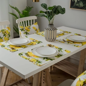 Lemon print double-sided placemats and cushions on a white table in a dining room