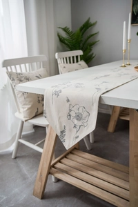 Detail of floral sketch pattern on beige linen table runner with fringes