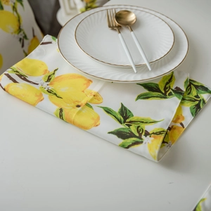 Lemon print placemat made of linen fabric on a white table with elegant dinnerware