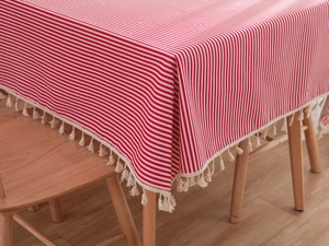 Detail of red and white striped cotton tablecloth with white decorative tassels on corner
