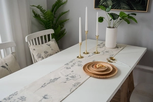 Detail of floral table runner in beige linen with vintage hand-drawn blue botanical patterns
