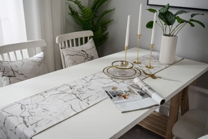 Detail of grey marble texture table runner and matching pillows on a white modern table