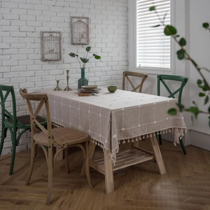 Plaid cotton linen tablecloth with white pompom embroidery and fringe on rectangular wood table