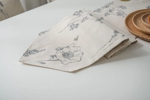Detailed macro view of cream linen table runner with gray floral and bee patterns