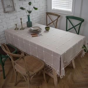 Linen rectangle tablecloth with white grid pattern and tassel trim in cozy home setting