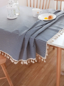 Close-up of blue and white striped linen tablecloth with cream tassels in a home setting