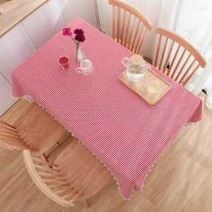 Minimalist red and white striped cotton tablecloth with white tassels on a wooden dining table