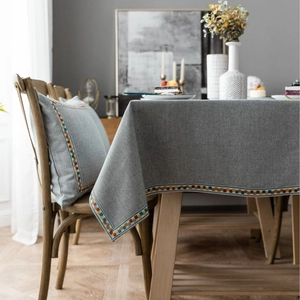 Gray-blue linen tablecloth with geometric embroidered borders and matching cushion cover