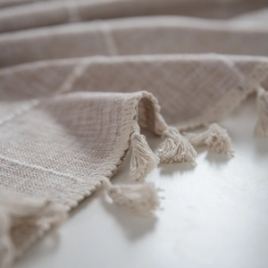 Beige plaid cotton linen tablecloth with elegant tassels shown in a stylish close-up shot