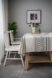 Detail of bohemian geometric black patterns on beige linen tablecloth with side drape