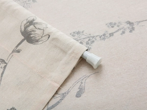 Close-up of rod pocket detail on linen fabric with sketched floral print for home doorway