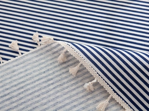 Close-up detail of navy blue and white striped cotton fabric with delicate fringe edges