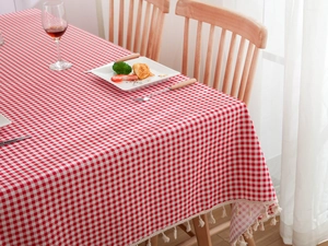 Detailed close-up of red and white plaid tablecloth featuring decorative white tassels fringe
